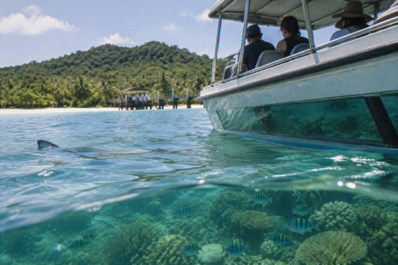 A glass-bottom boat gliding over a coral reef off Green Island with fish and coral visible through the water