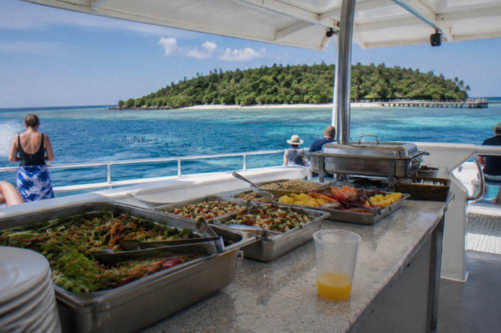 Buffet lunch served aboard a reef cruise catamaran at an outdoor deck table